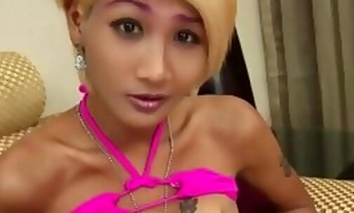Blonde ladyboy in pink bikini jerks off her small cock on the couch
