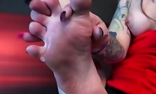 Tattooed shemale plays with her sexy feet and masturbates